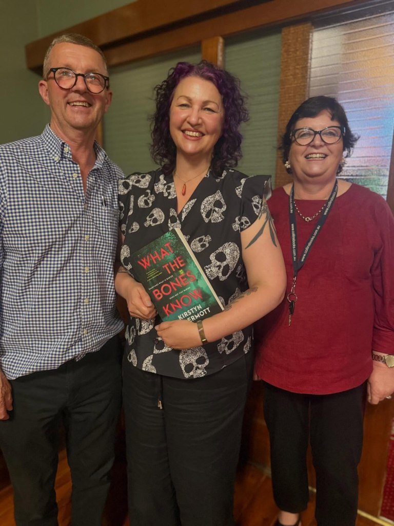 Kirstyn McDermott holding a copy of her novel, with Lyle and Tracey from Collins Booksellers.
Photo by Collins Booksellers