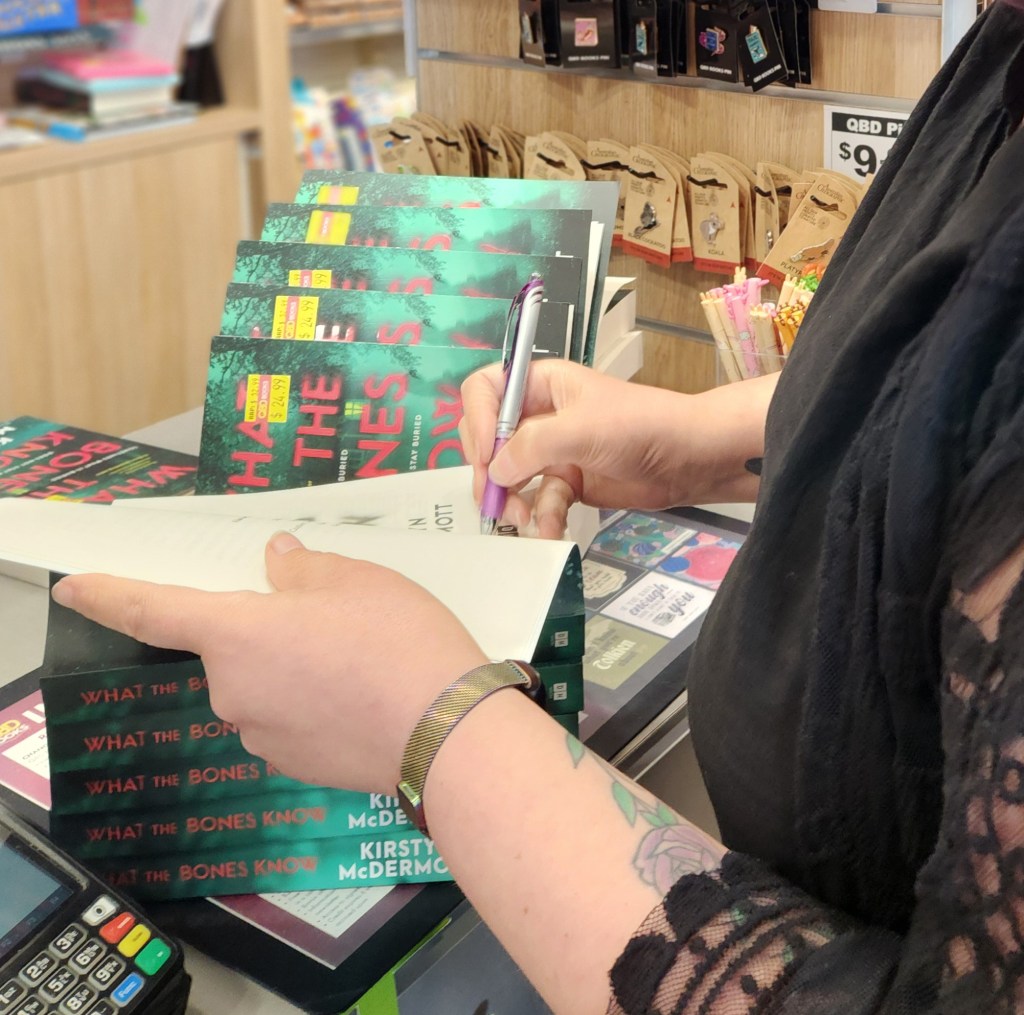 Kirstyn McDermott signing in-store copies of What the Bones Know with a purple pen (of course).